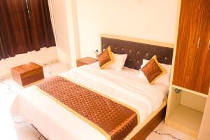 ein Schlafzimmer mit einem Bett mit weißer Bettwäsche und braunen Kissen in der Unterkunft The Comfort Home Stay Ranthambhore in Sawāi Mādhopur