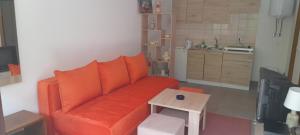 sala de estar con sofá naranja y mesa en Apartman NeSa Boracko jezero, en Konjic