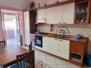 a kitchen with white cabinets and a wooden table at Maridea - Fragolino in Ponza