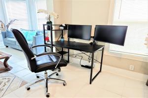 a desk with two monitors and a chair in a room at CasaAzul-2605A-Couples Retreat By Pleasure Pier, Beach, Seawall,a block away 5 Minutes from Strands and Cruise Terminal in Galveston
