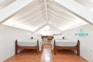 two beds in a attic room with white ceilings at In Burgus guest house in Viana do Castelo