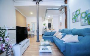 uma sala de estar com um sofá azul e uma televisão em Apartamento Palacio Real de Madrid, histórico em Madri