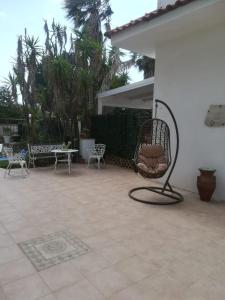 um pátio com cadeiras de baloiço e uma mesa e cadeiras em Villa Lucia em Santa Maria Del Focallo