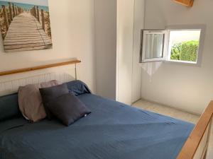 1 dormitorio con cama azul y ventana en Pavillons 7 et 56 Narbonne Plage, en Narbonne-Plage