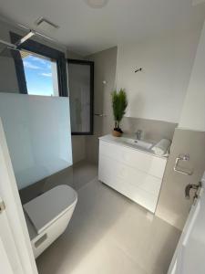 bagno bianco con servizi igienici e lavandino di Lujosa casa en primera línea playa increibles vistas mar a Laredo