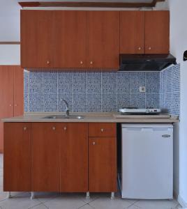 a kitchen with wooden cabinets and a sink and a dishwasher at Studio's Stelios in Leptokaria