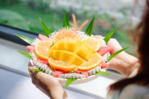 a woman holding a plate of fruit and vegetables at Tuong Boutique Resort Mui ne in Mui Ne