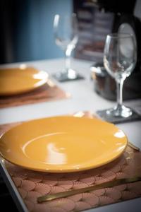 une assiette jaune sur une table avec deux verres à vin dans l'établissement Welcomeagen*The Artist*Clim*Fibre, à Agen