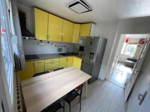 eine Küche mit gelben Schränken und einem Holztisch in der Unterkunft Maison de ville,RER A 20 min pour Paris/Disneyland in Neuilly-sur-Marne