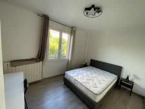 Schlafzimmer mit einem Bett und einem Fenster in der Unterkunft Maison de ville,RER A 20 min pour Paris/Disneyland in Neuilly-sur-Marne