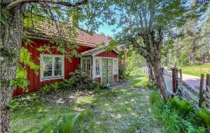 ein rotes Haus mit einem Zaun neben einem Baum in der Unterkunft Stunning Home In Ydre With Kitchen 