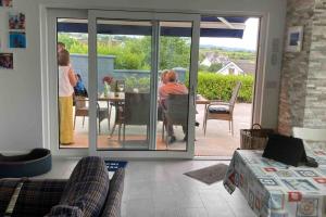 eine Gruppe von Personen steht in einem Wohnzimmer mit einer Glasschiebetür in der Unterkunft Magnificent Views over Dungarvan Bay, Ring, Waterford , Panoramic Sea Views, in Dungarvan