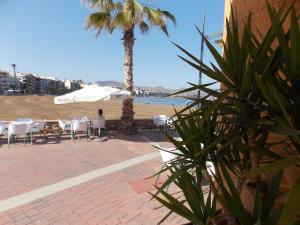 einen Strand mit Tischen, Stühlen und einer Palme in der Unterkunft Puertosol in Puerto de Mazarrón