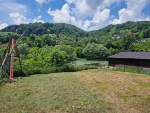 an empty field with a barn and mountains in the background at Apartman Sofija in Banja Luka