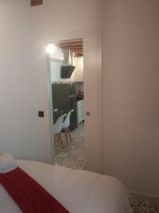 a bedroom with a white bed and a kitchen at SEÑORÍO DE ORGAZ III in Toledo