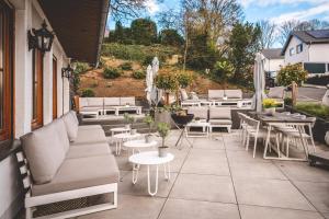 a patio with white furniture and tables and chairs at Landidyll Hotel Weidenbrück & SPA in Swisttal