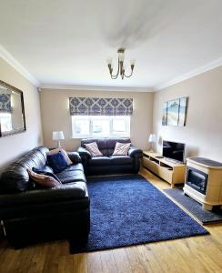 een woonkamer met een leren bank en een blauw tapijt bij 26 Woodgrove Drive in Inverness