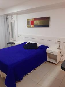 Un dormitorio con una cama azul y una pintura en la pared en Hermoso departamento céntrico! en San Miguel de Tucumán