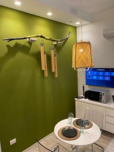 una cocina con una pared verde y una mesa con copas de vino en Home3 beb appartments, en Bisceglie