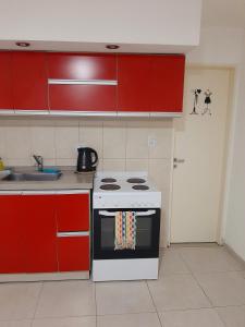 cocina con estufa blanca y armarios rojos en Hermoso departamento céntrico! en San Miguel de Tucumán