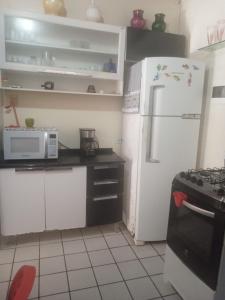 a kitchen with a white refrigerator and a microwave at Condomínio Amanda Travassos in Jaguaribe