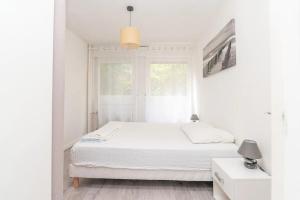 a white bedroom with a bed and a window at Le charme Chalonnais in Chalon-sur-Saône