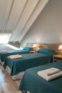 Habitación con 3 camas con sábanas y lámparas verdes en Arenas Cariló by bund en Cariló