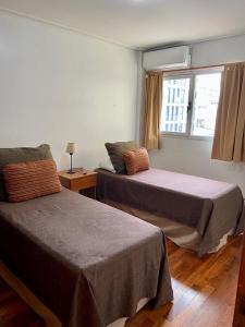 two beds in a room with a window and a bed sidx sidx sidx at Departamentos de Categoría, Santa Fé y Alberti in Mar del Plata