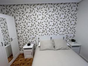 een kleine slaapkamer met een wit bed en behang bij La posada de Don Pelayo in Noreña