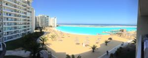 uma vista para uma praia com guarda-sóis e uma piscina em DEPARTAMENTO EN RESORT LAGUNA DEL MAR em La Serena