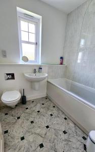 een badkamer met een bad, een toilet en een wastafel bij 26 Woodgrove Drive in Inverness