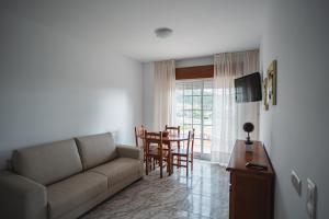 een woonkamer met een bank en een tafel en stoelen bij Apartamentos Coral Do Mar I in Portonovo