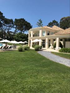 duży biały dom z parasolami na trawniku w obiekcie Monoambiente Green Park- Solanas w mieście Punta del Este