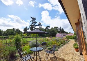 un patio con mesa, sillas y sombrilla en Akenfield Cottage, Letheringham, en Kettleburgh