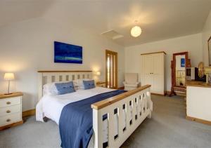 a bedroom with a large bed with a blue blanket at Akenfield Cottage, Letheringham in Kettleburgh