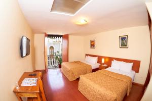 Habitación de hotel con 2 camas y mesa en Hotel Santa Rosa, en Arequipa