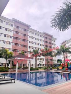 a hotel with a swimming pool in front of a building at Cozy Belle Suite Relaxing Place at SMDC Hope Residences in Trece Martires