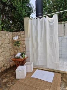 a shower with a white curtain and a table at Villa SeaBreeze in Rogoznica