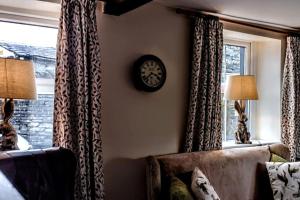 - un salon avec un canapé et un réveil sur le mur dans l'établissement Riverside Cottage, Helwith Bridge, Yorkshire Dales, à Horton in Ribblesdale