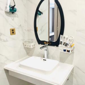 W białej łazience znajduje się umywalka i lustro. w obiekcie LONG VŨ HOTEL w mieście Lạng Sơn