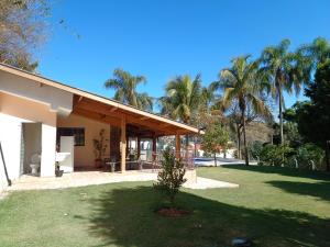 una casa con un patio verde con palmeras en Chácara Rancho Fundo en Águas de Lindóia