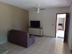 a living room with a couch and a flat screen tv at Chácara Rancho Fundo in Águas de Lindoia