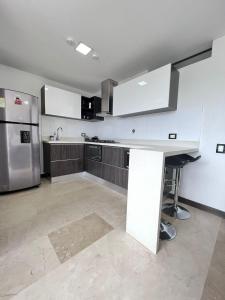 a kitchen with white cabinets and a stainless steel refrigerator at Large Apartment High Views and Balcony in Medellín
