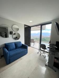 a living room with a blue couch and a desk at Large Apartment High Views and Balcony in Medellín