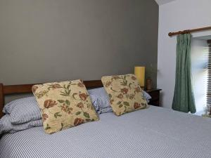 Una cama con dos almohadas encima. en Rustic Vintage Cottage: Near Waterfall Country, en Pont-Nedd-Fechan