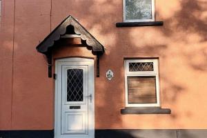 a building with a white door and two windows at Rustic Vintage Cottage: Near Waterfall Country in Pont-Nedd-Fechan