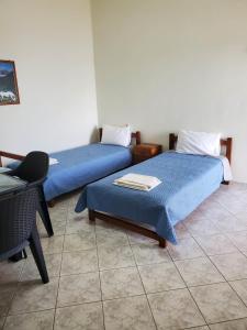 two beds in a room with blue sheets and a chair at Villa Koutsakis in Kaloi Limenes
