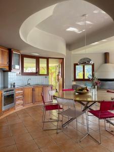 a kitchen with a dining room table and red chairs at Round Family Villa near Ancient Olympia & the Sea in Káto Samikón