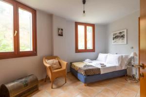 um quarto com uma cama, uma cadeira e 2 janelas em Round Family Villa near Ancient Olympia & the Sea em Káto Samikón