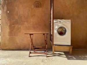 uma máquina de lavar roupa e uma cadeira ao lado de uma parede em Round Family Villa near Ancient Olympia & the Sea em Káto Samikón
